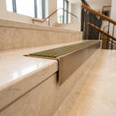 Solid Brass Stair Nosing 71mm Tread Square Front Slimline in Antique Brass finish with Olive Castellated insert fitted on a hotel lobby staircase with cream marble treads
