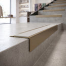Solid Brass Stair Nosing 71mm Tread Square Front Slimline in Antique Brass finish with Polar Grey Smooth Textured insert fitted on a retail store staircase with polished concrete treads