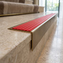 Solid Brass Stair Nosing 71mm Tread Square Front Slimline in Antique Brass finish with Poppy Castellated insert fitted on a hotel lobby staircase with cream marble treads