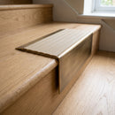 Solid Brass Stair Nosing 71mm Tread Square Front Slimline in Antique Brass finish with Porth Stone Castellated insert fitted on a residential oak staircase