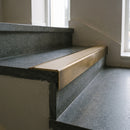 Solid Brass Stair Nosing 71mm Tread Square Front Slimline in Antique Brass finish with Porth Stone Smooth Textured insert fitted on a public building staircase with dark stone treads