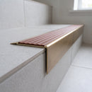 Solid Brass Stair Nosing 71mm Tread Square Front Slimline in Antique Brass finish with Rustic Castellated insert fitted on a modern office reception staircase with porcelain tile treads