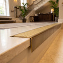 Solid Brass Stair Nosing 71mm Tread Square Front Slimline in Antique Brass finish with Satin Brass insert fitted on a hotel lobby staircase with cream marble treads