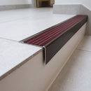 Solid Brass Stair Nosing 71mm Tread Square Front Slimline in Antique Bronze finish with Claret Castellated insert fitted on a modern office reception staircase with porcelain tile treads