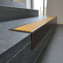 Solid Brass Stair Nosing 71mm Tread Square Front Slimline in Antique Bronze finish with Gold Castellated insert fitted on a public building staircase with dark stone treads