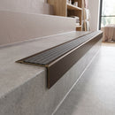 Solid Brass Stair Nosing 71mm Tread Square Front Slimline in Antique Bronze finish with Granite Castellated insert fitted on a retail store staircase with polished concrete treads