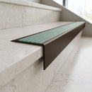 Solid Brass Stair Nosing 71mm Tread Square Front Slimline in Antique Bronze finish with Jade Castellated insert fitted on a hotel lobby staircase with cream marble treads