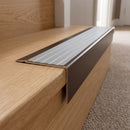 Solid Brass Stair Nosing 71mm Tread Square Front Slimline in Antique Bronze finish with Light Grey Castellated insert fitted on a residential oak staircase