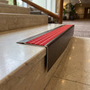 Solid Brass Stair Nosing 71mm Tread Square Front Slimline in Antique Bronze finish with Poppy Castellated insert fitted on a hotel lobby staircase with cream marble treads