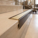 Solid Brass Stair Nosing 71mm Tread Square Front Slimline in Antique Bronze finish with Satin Brass insert fitted on a hotel lobby staircase with cream marble treads