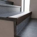 Solid Brass Stair Nosing 71mm Tread Square Front Slimline in Antique Bronze finish with White Castellated insert fitted on a public building staircase with dark stone treads