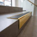 Solid Brass Stair Nosing 71mm Tread Square Front Slimline in Polished Brass finish with Black Smooth Textured insert fitted on a retail store staircase with polished concrete treads