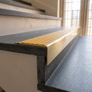 Solid Brass Stair Nosing 71mm Tread Square Front Slimline in Polished Brass finish with Gold Castellated insert fitted on a public building staircase with dark stone treads