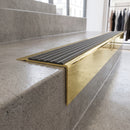 Solid Brass Stair Nosing 71mm Tread Square Front Slimline in Polished Brass finish with Granite Castellated insert fitted on a retail store staircase with polished concrete treads
