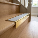Solid Brass Stair Nosing 71mm Tread Square Front Slimline in Polished Brass finish with Light Grey Castellated insert fitted on a residential oak staircase