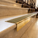 Solid Brass Stair Nosing 71mm Tread Square Front Slimline in Polished Brass finish with Olive Castellated insert fitted on a hotel lobby staircase with cream marble treads