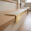 Solid Brass Stair Nosing 71mm Tread Square Front Slimline in Polished Brass finish with Porth Stone Castellated insert fitted on a residential oak staircase