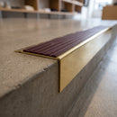 Solid Brass Stair Nosing 71mm Tread Square Front Slimline in Polished Brass finish with Regency Castellated insert fitted on a retail store staircase with polished concrete treads
