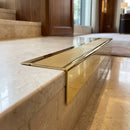 Solid Brass Stair Nosing 71mm Tread Square Front Slimline in Polished Brass finish with Satin Brass insert fitted on a hotel lobby staircase with cream marble treads