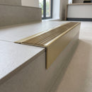 Solid Brass Stair Nosing 71mm Tread Square Front Slimline in Satin Brass finish with Antique Brass insert fitted on a modern office reception staircase with porcelain tile treads