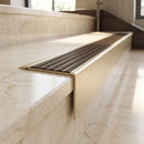 Solid Brass Stair Nosing 71mm Tread Square Front Slimline in Satin Brass finish with Antique Bronze insert fitted on a hotel lobby staircase with cream marble treads