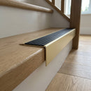 Solid Brass Stair Nosing 71mm Tread Square Front Slimline in Satin Brass finish with Black Castellated insert fitted on a residential oak staircase