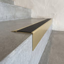 Solid Brass Stair Nosing 71mm Tread Square Front Slimline in Satin Brass finish with Black Smooth Textured insert fitted on a retail store staircase with polished concrete treads