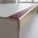 Solid Brass Stair Nosing 71mm Tread Square Front Slimline in Satin Brass finish with Claret Castellated insert fitted on a modern office reception staircase with porcelain tile treads