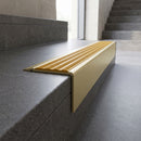 Solid Brass Stair Nosing 71mm Tread Square Front Slimline in Satin Brass finish with Gold Castellated insert fitted on a public building staircase with dark stone treads