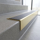 Solid Brass Stair Nosing 71mm Tread Square Front Slimline in Satin Brass finish with Granite Castellated insert fitted on a retail store staircase with polished concrete treads