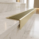 Solid Brass Stair Nosing 71mm Tread Square Front Slimline in Satin Brass finish with Olive Castellated insert fitted on a hotel lobby staircase with cream marble treads