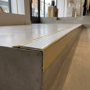 Solid Brass Stair Nosing 71mm Tread Square Front Slimline in Satin Brass finish with Polar Grey Smooth Textured insert fitted on a retail store staircase with polished concrete treads