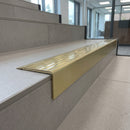 Solid Brass Stair Nosing 71mm Tread Square Front Slimline in Satin Brass finish with Polished Brass insert fitted on a modern office reception staircase with porcelain tile treads