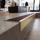 Solid Brass Stair Nosing 71mm Tread Square Front Slimline in Satin Brass finish with Regency Castellated insert fitted on a retail store staircase with polished concrete treads