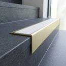 Solid Brass Stair Nosing 71mm Tread Square Front Slimline in Satin Brass finish with White Castellated insert fitted on a public building staircase with dark stone treads