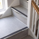 Square edge aluminium stair nosing with a dark charcoal Mor Grip insert in bright polished finish fitted on a domestic staircase finished in light grey vinyl