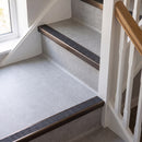 Square edge aluminium stair nosing with a dark charcoal Mor Grip insert in dark bronze finish fitted on a domestic staircase finished in light grey vinyl