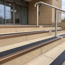 Satin bronze 56mm square aluminium stair nosing with coal (black) exterior grip insert on buff concrete entrance steps outside a health centre