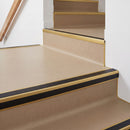 Square aluminium stair nosing with black insert in satin gold finish fitted on a shop entrance stair with beige lino