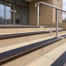 Dark bronze 56mm square aluminium stair nosing with coal (black) exterior grip insert on buff concrete entrance steps outside a health centre