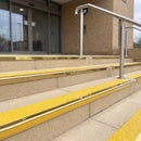 Mirror polished gold 56mm square aluminium stair nosing with brimstone (safety yellow) exterior grip insert on buff concrete entrance steps outside a health centre