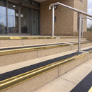 Mirror polished gold 56mm square aluminium stair nosing with coal (black) exterior grip insert on buff concrete entrance steps outside a health centre