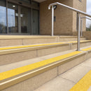 Satin gold 56mm square aluminium stair nosing with brimstone (safety yellow) exterior grip insert on buff concrete entrance steps outside a health centre