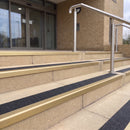 Satin gold 56mm square aluminium stair nosing with coal (black) exterior grip insert on buff concrete entrance steps outside a health centre