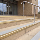 Satin gold 56mm square aluminium stair nosing with everest (light grey) exterior grip insert on buff concrete entrance steps outside a health centre