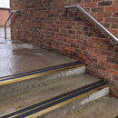Square edge aluminium stair nosing with black gritted exterior grip insert in mirrorflect gold finish fitted on covered external concrete steps