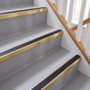 Square aluminium stair nosing with black insert in satin gold finish fitted on a home staircase with grey vinyl