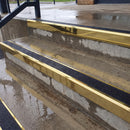 Square edge aluminium stair nosing with black gritted exterior grip insert in mirrorflect gold finish fitted on covered external concrete steps