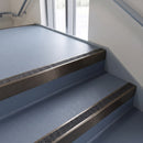 Square edge aluminium stair nosing with a dark charcoal Mor Grip insert in dark bronze finish fitted on a public building stair finished in blue-grey safety vinyl