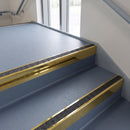 Square edge aluminium stair nosing with a dark charcoal Mor Grip insert in mirrorflect gold finish fitted on a public building stair finished in blue-grey safety vinyl